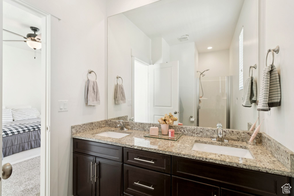 Ensuite bathroom featuring double vanity, a stall shower, and ceiling fan