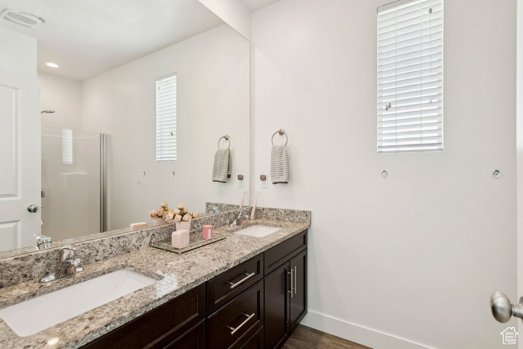 Full bathroom with double vanity, baseboards, wood finished floors, and an enclosed shower