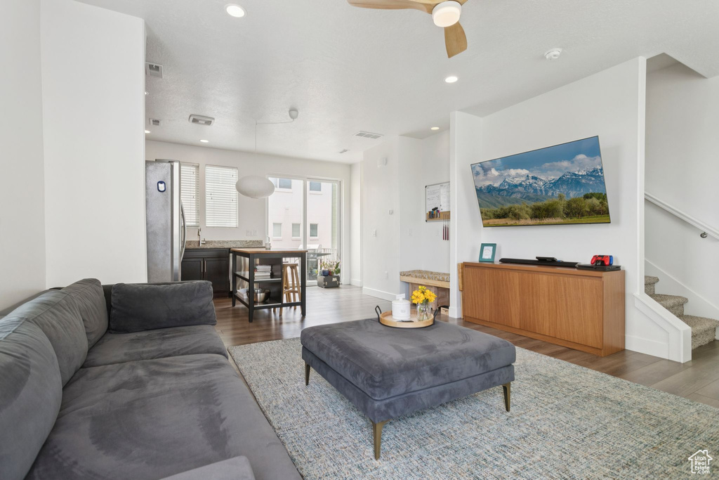 Living room with wood finished floors, stairway, ceiling fan, baseboards, and recessed lighting