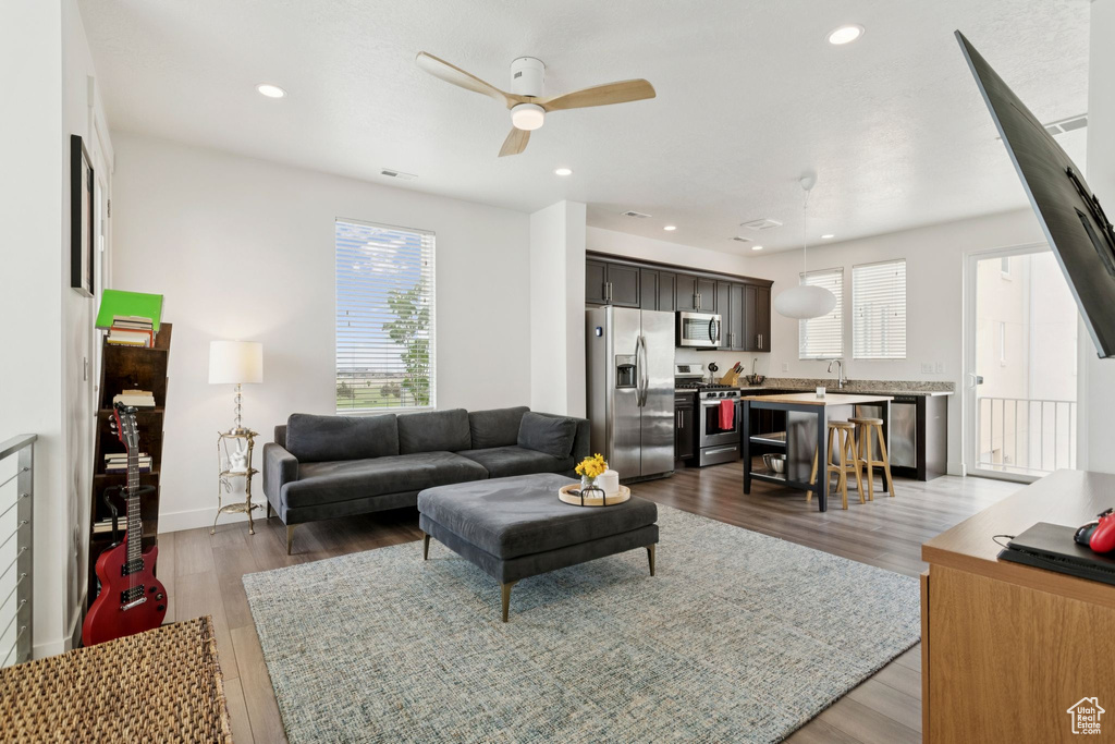 Living area with a ceiling fan, wood finished floors, recessed lighting, and baseboards