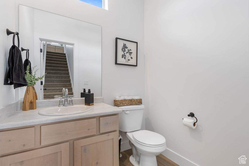 Bathroom featuring toilet, vanity, wood finished floors, and baseboards