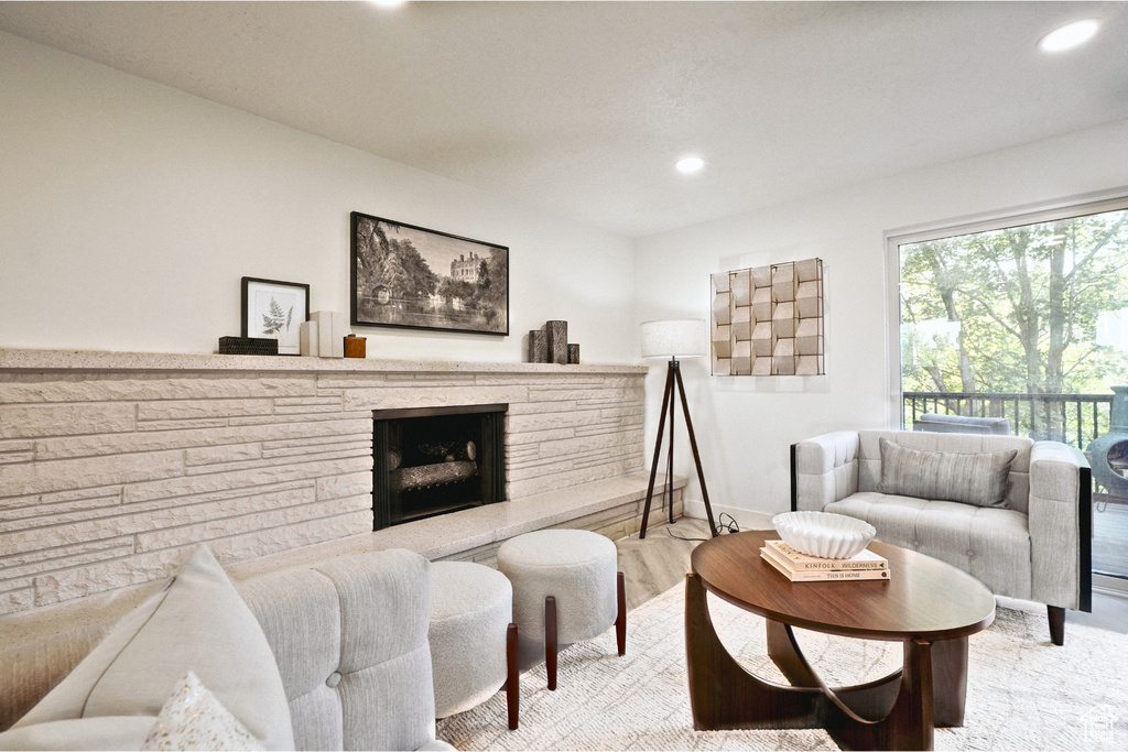 Living room with a stone fireplace, recessed lighting, baseboards, and wood finished floors