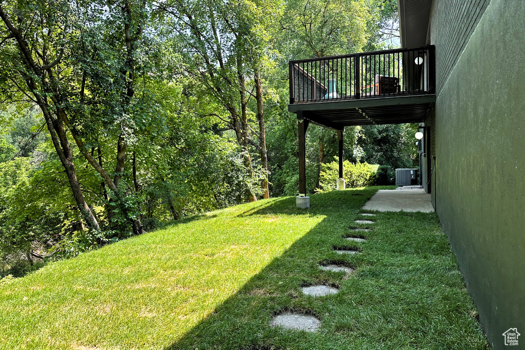 View of green lawn featuring central AC unit and a wooden deck