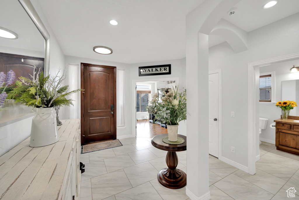 Entryway with arched walkways, light marble finish flooring, and baseboards