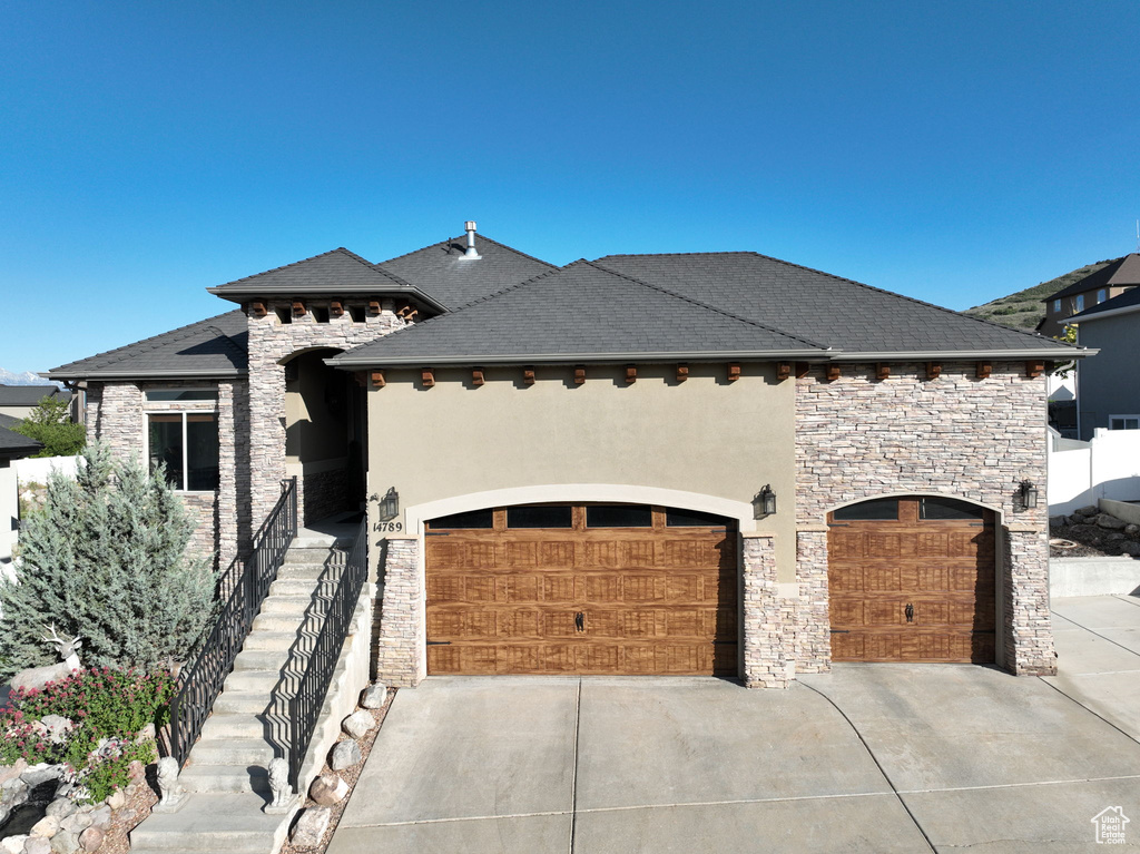 French country home with stone siding, concrete driveway, stucco siding, and a garage