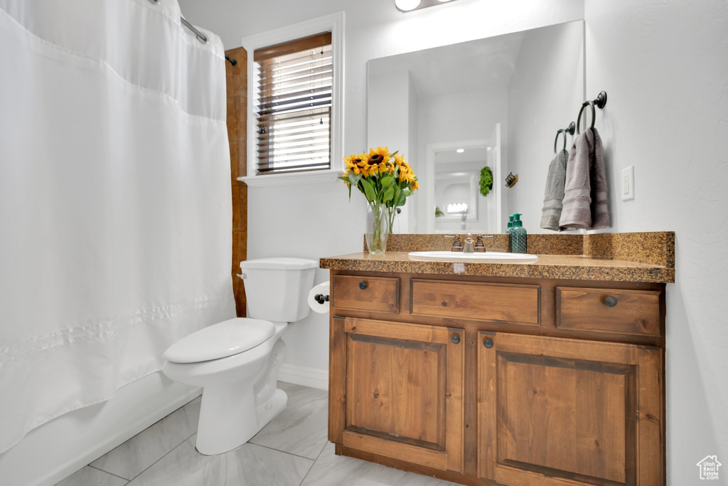 Bathroom featuring vanity, toilet, and baseboards