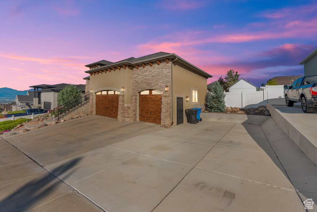 View of side of property with stone siding, driveway, and an attached garage