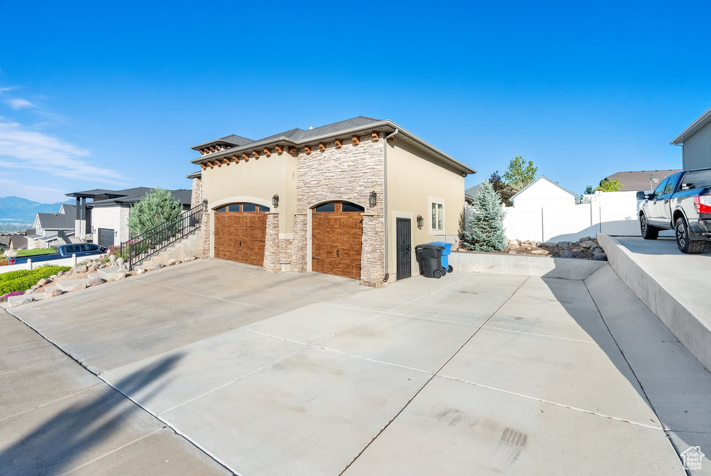 View of home\\\'s exterior with stone siding, driveway, and a garage