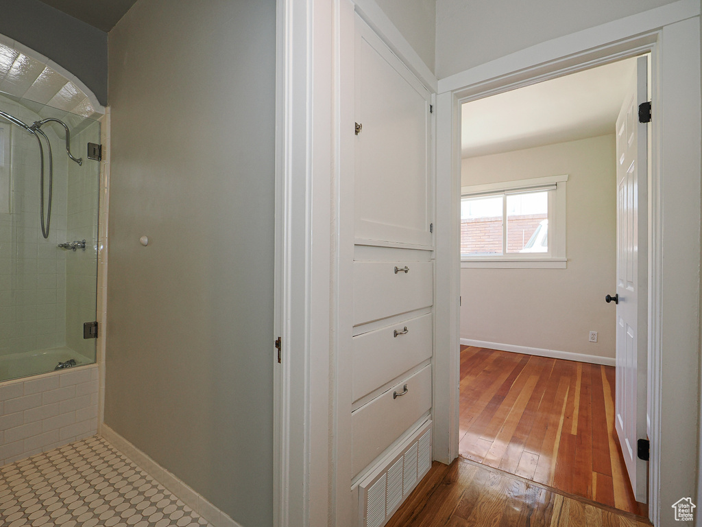 Full bath with shower / tub combination, wood finished floors, and baseboards