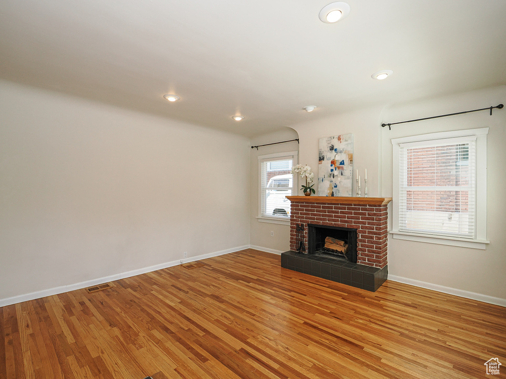 Unfurnished living room featuring light wood-style flooring, a brick fireplace, baseboards, and recessed lighting