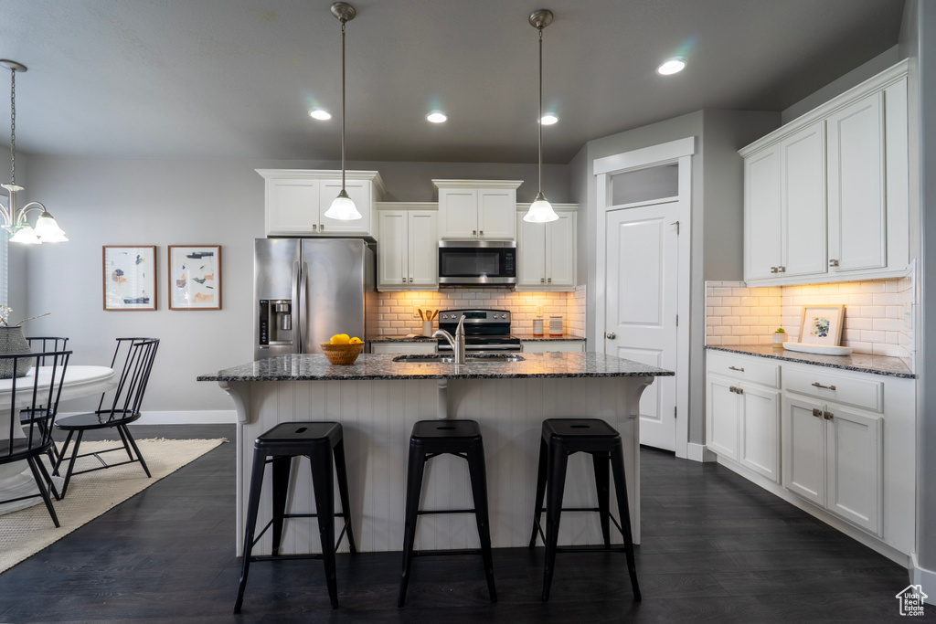 Kitchen with appliances with stainless steel finishes, a sink, baseboards, a breakfast bar area, and recessed lighting