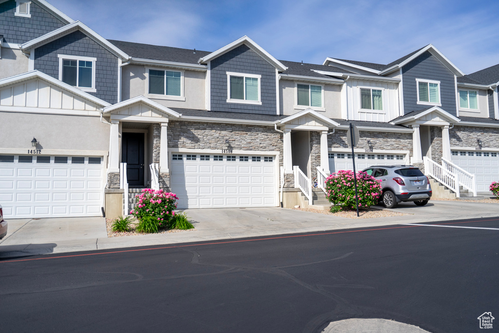Multi unit property with board and batten siding, stone siding, concrete driveway, and an attached garage