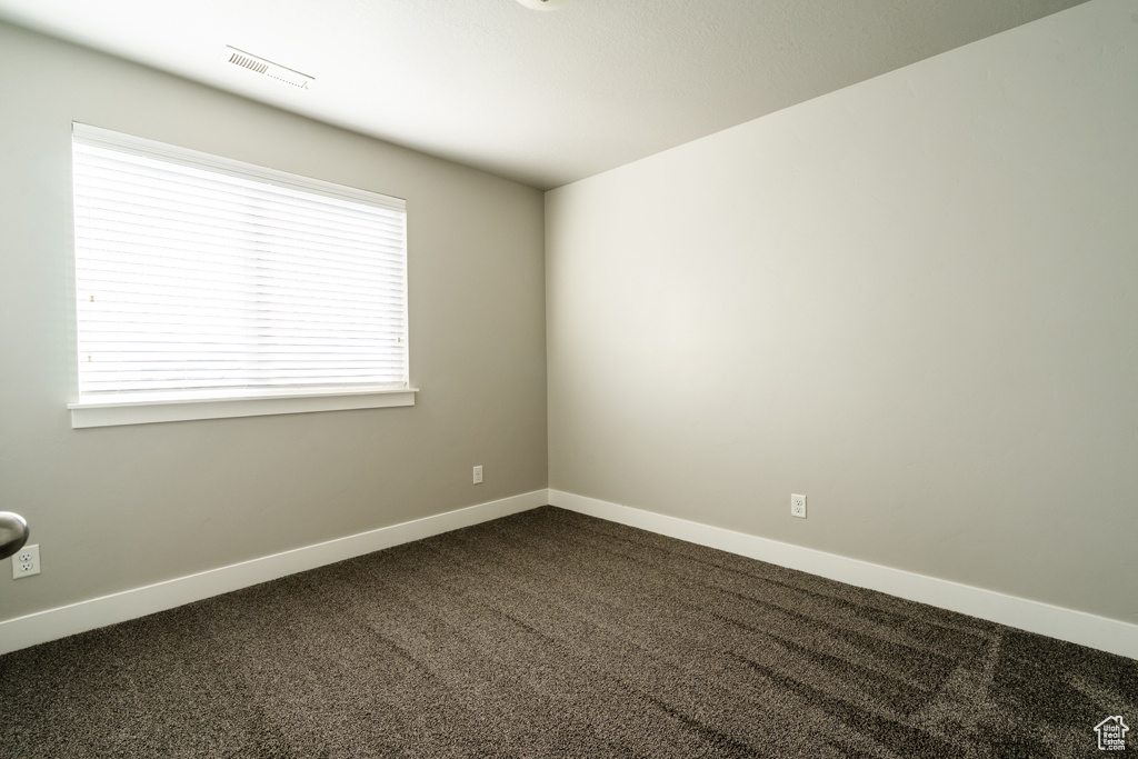 Empty room with dark carpet and baseboards