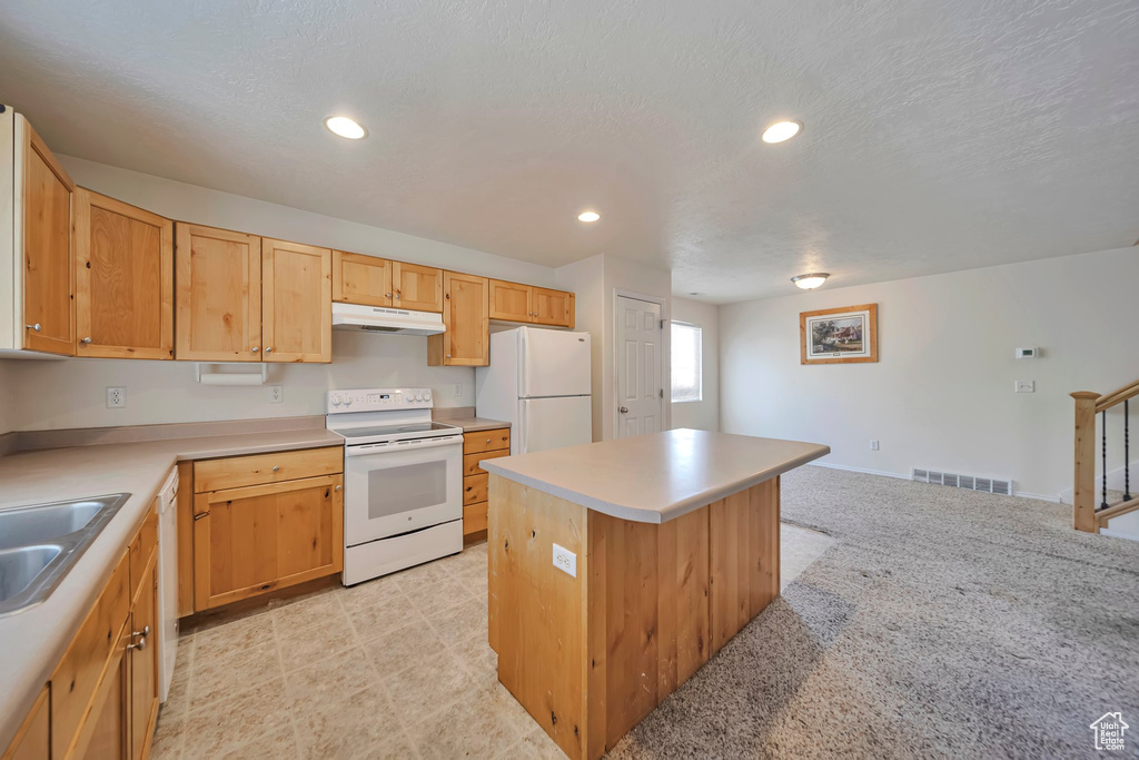 Kitchen featuring white appliances, under cabinet range hood, a sink, a center island, and light countertops