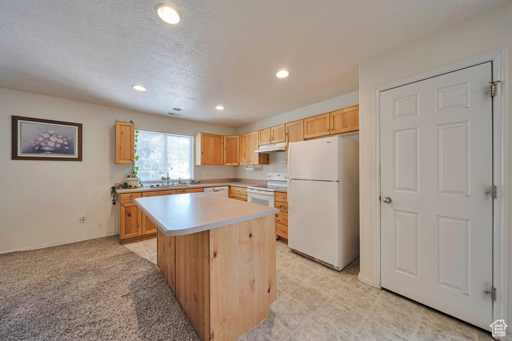 Kitchen with white appliances, light brown cabinetry, under cabinet range hood, recessed lighting, and light countertops