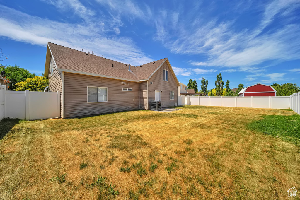 Rear view of property featuring central air condition unit and a shingled roof