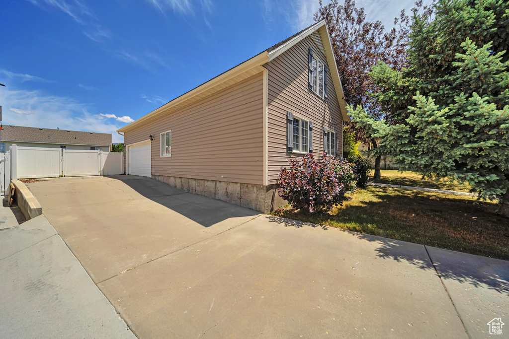 View of side of property featuring an attached garage and concrete driveway