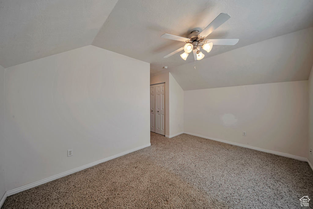 Additional living space with lofted ceiling, a ceiling fan, light carpet, and baseboards