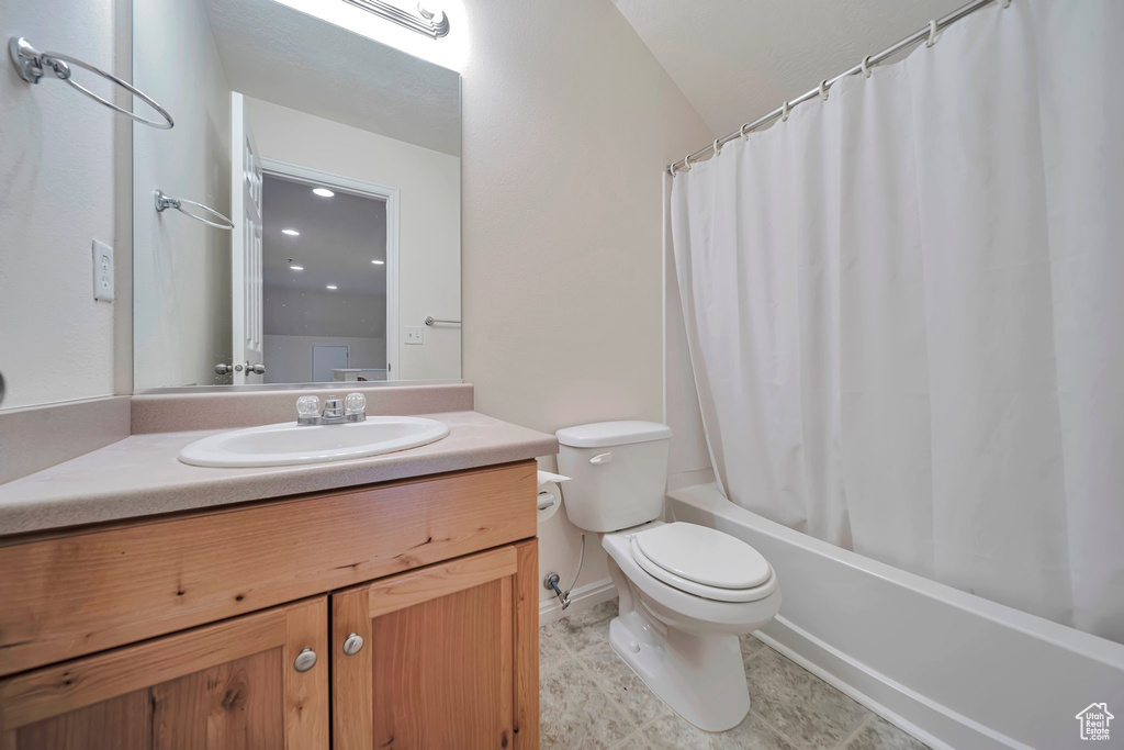 Full bathroom with vanity, toilet, shower / tub combo with curtain, and baseboards