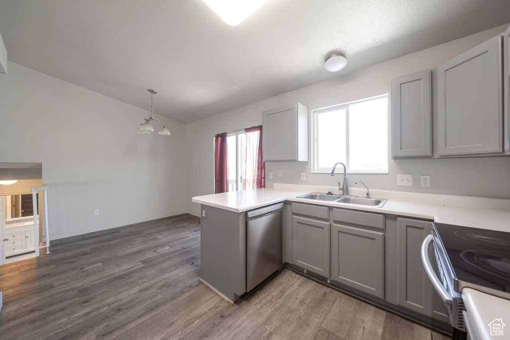 Kitchen with a sink, stainless steel appliances, gray cabinets, a peninsula, and vaulted ceiling