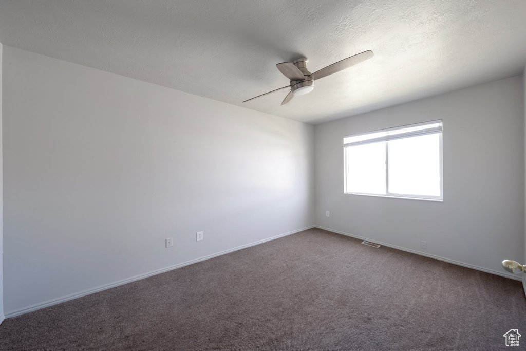 Carpeted empty room with a ceiling fan and baseboards