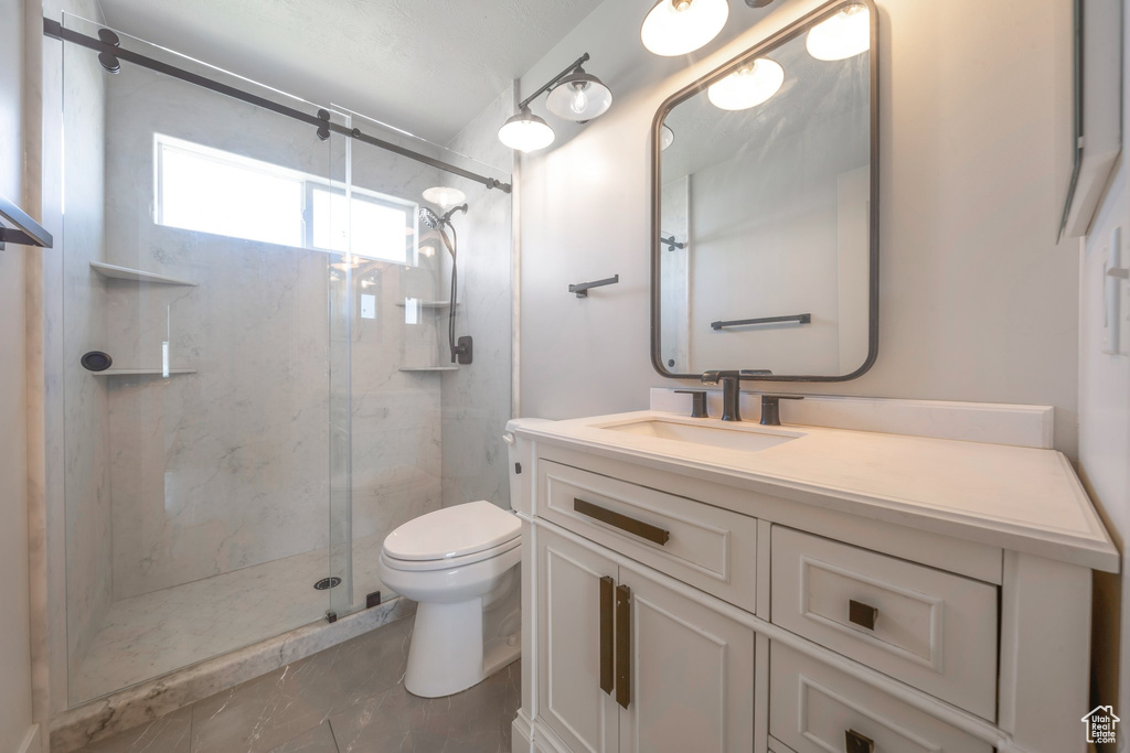 Bathroom featuring toilet, a marble finish shower, and vanity