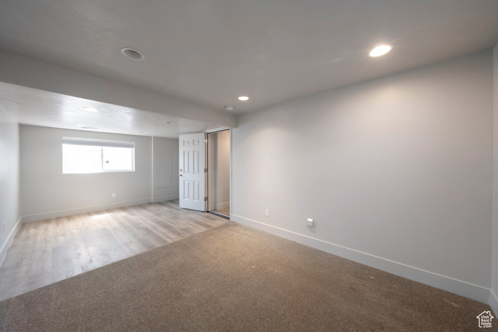 Empty room with baseboards, recessed lighting, light wood-style floors, and light colored carpet
