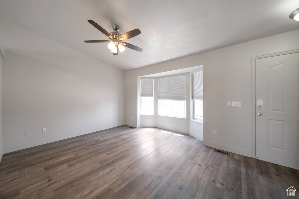 Spare room with ceiling fan, wood finished floors, baseboards, and lofted ceiling