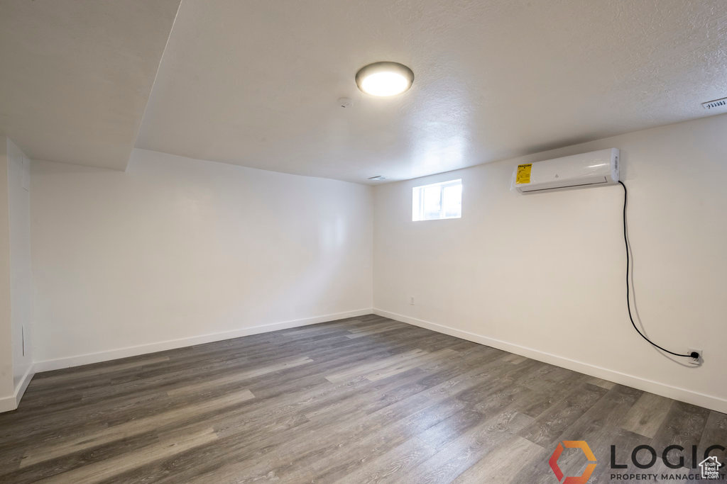 Below grade area featuring a wall unit AC, dark wood-style floors, and baseboards