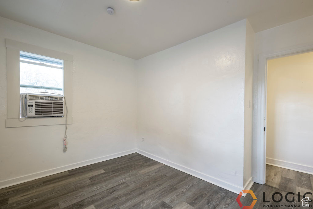 Spare room featuring dark wood-style flooring, cooling unit, baseboards, and a smoke detector