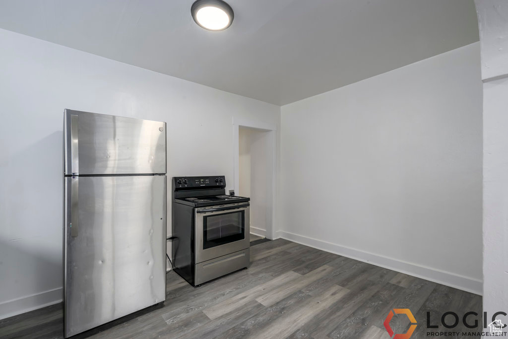 Kitchen with appliances with stainless steel finishes, dark wood-style floors, and baseboards