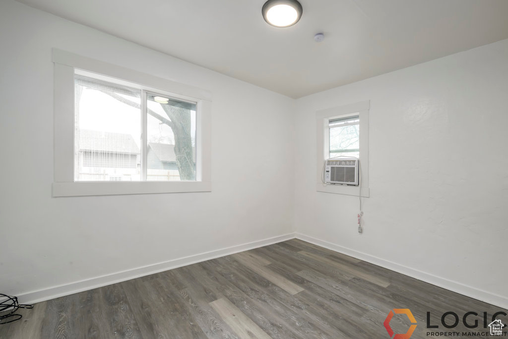 Unfurnished room with baseboards, cooling unit, and dark wood finished floors