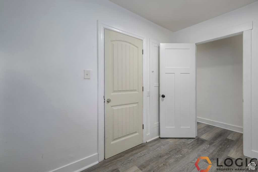 Unfurnished bedroom featuring dark wood-style flooring and baseboards