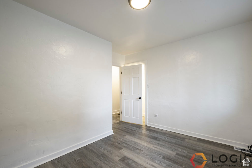 Empty room with dark wood-type flooring and baseboards