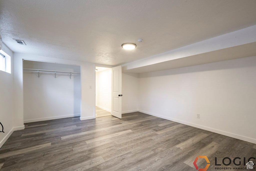 Unfurnished bedroom with dark wood-style floors, baseboards, a closet, and a textured ceiling