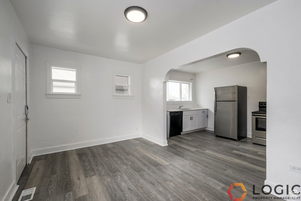 Kitchen with stainless steel appliances, arched walkways, dark wood-style floors, and a sink