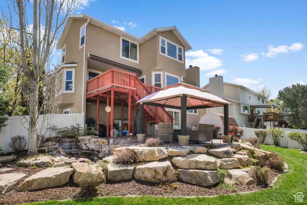 Back of house featuring a gazebo, stucco siding, stairs, and a wooden deck