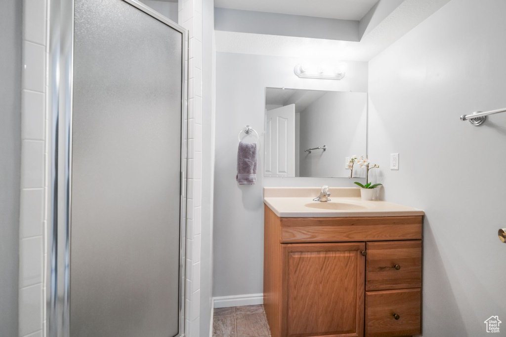 Bathroom with a stall shower, vanity, and baseboards