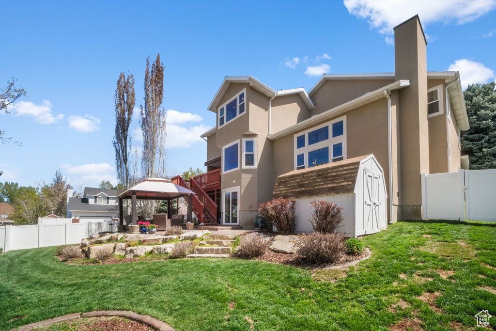 Rear view of property featuring a gazebo, a chimney, and stucco siding