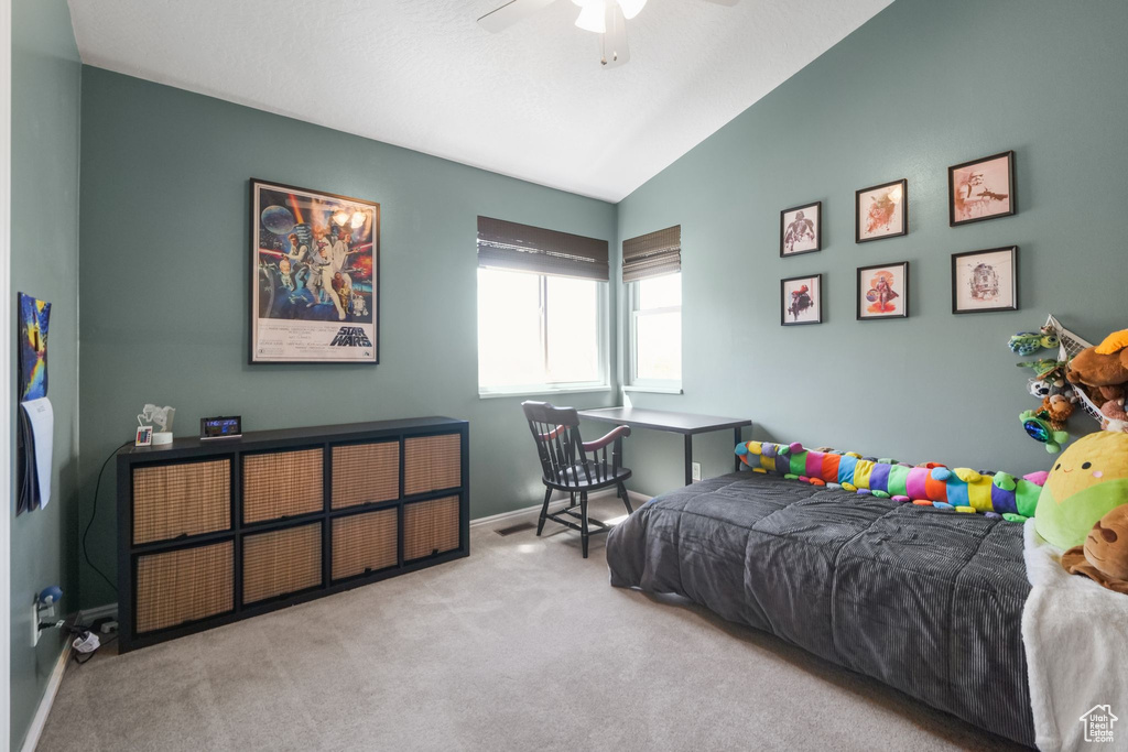 Carpeted bedroom featuring lofted ceiling, baseboards, and a ceiling fan