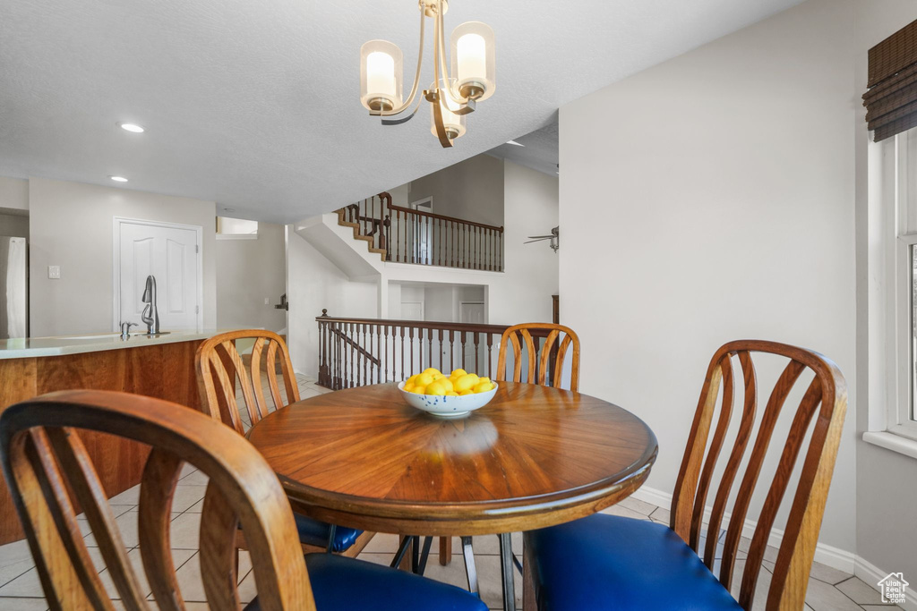 Dining space featuring light tile patterned floors, baseboards, recessed lighting, stairs, and a chandelier
