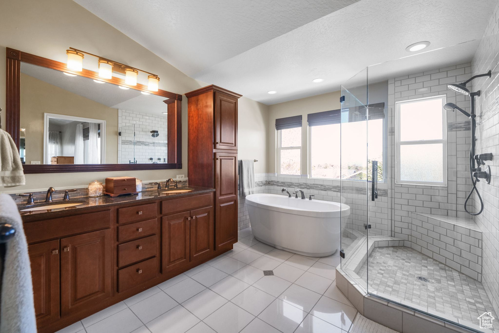 Full bathroom with a stall shower, a freestanding tub, double vanity, tile patterned flooring, and tile walls