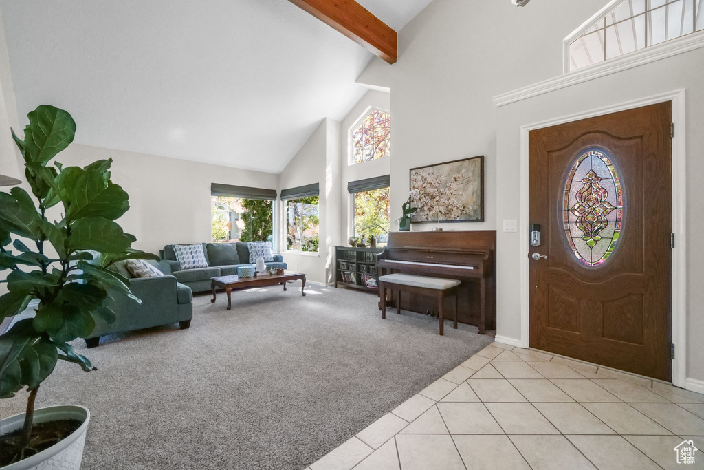 Carpeted entryway featuring high vaulted ceiling, beam ceiling, tile patterned floors, and baseboards