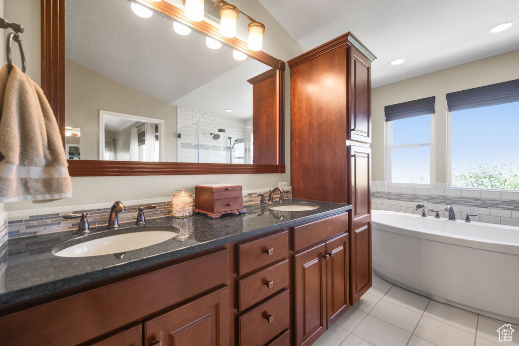 Bathroom with tile patterned floors, double vanity, a soaking tub, a stall shower, and vaulted ceiling