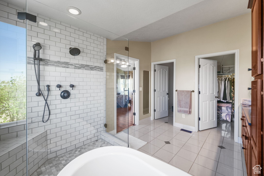 Full bath with a stall shower, tile patterned flooring, a walk in closet, and baseboards