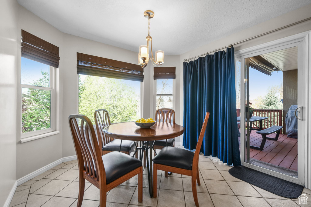 Dining area with a chandelier, light tile patterned floors, and baseboards