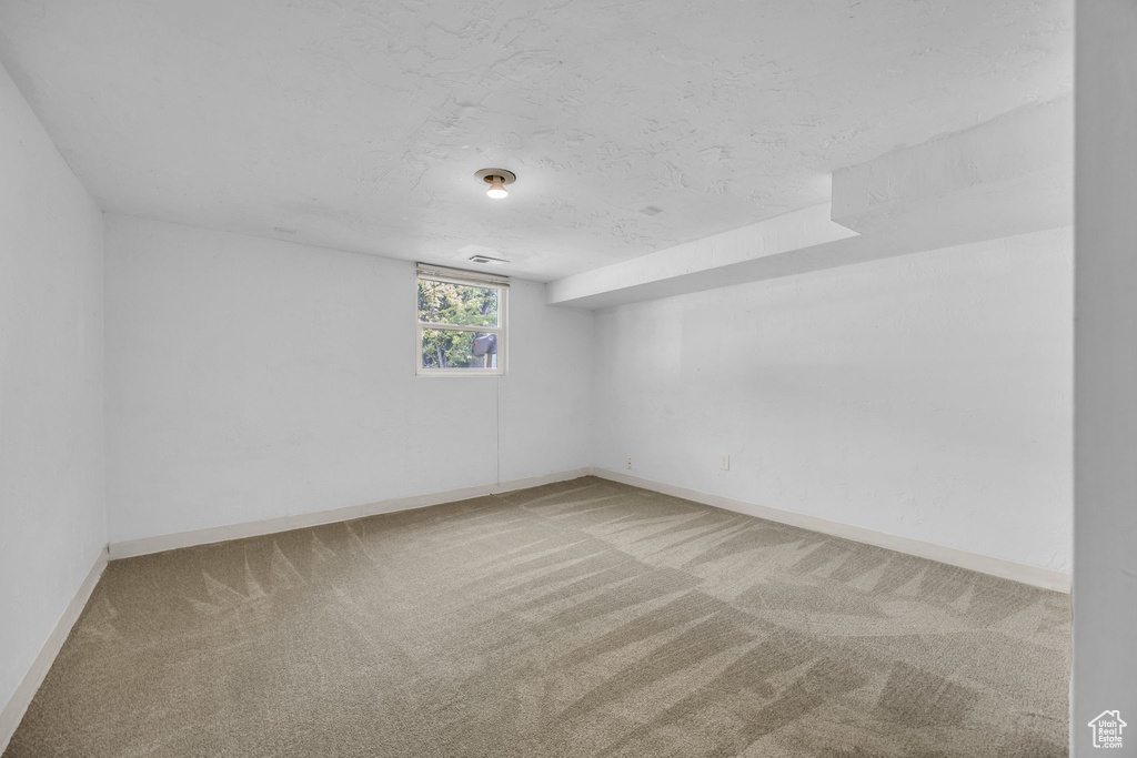 Unfurnished room with carpet, baseboards, and a textured ceiling