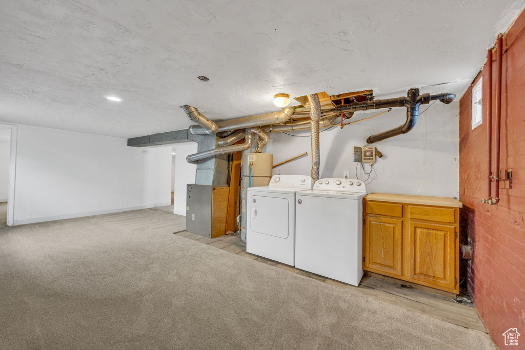 Laundry room with washer and dryer, cabinet space, light carpet, and heating unit