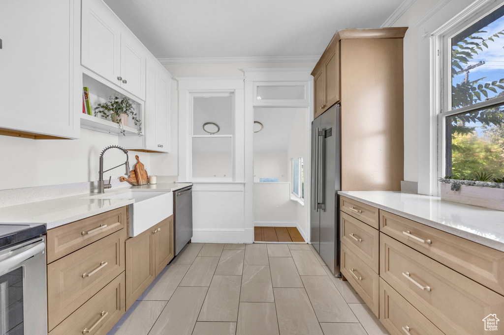 Kitchen with a sink, stainless steel appliances, light countertops, crown molding, and open shelves