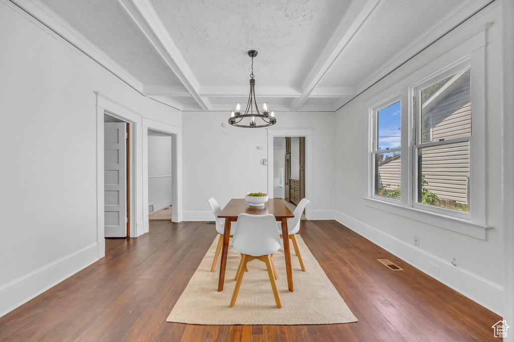 Dining area featuring a chandelier, dark wood-style floors, beamed ceiling, baseboards, and coffered ceiling